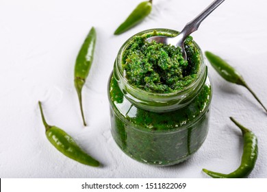 Hot Chili Pepper Paste. Green Sauce In Glass Jar On White Background. Adjika Or Ajika In Georgian Cuisine Or Harissa In Arabic Cuisine.