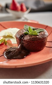 Hot Chocolate Fondant with Mint Leaves and Berries on Terracotta Plate Close Up. Fresh Brownie Dessert with Melted Dark Cocoa Mousse. Small Chocolate Cake with Crunchy Rind and Mellow Filling - Shutterstock ID 1130631320