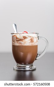 Hot chocolate in glass mug with whipped cream and a cherry