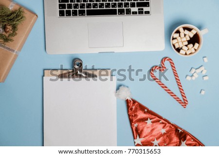 Hot Cocoa with marshmallows and laptop, candies on a blue table. top view, Christmas, flat lay
