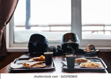 Hot Coffee And Cup Of Tea With Pancakes And Jam On A Salver. Quick Lunch Of Two Skiers On Mountain Ski Resort In Wooden Lodge Bar. Casual Dinner Of A Snowboarder. Two Helmets With Goggles On Table 