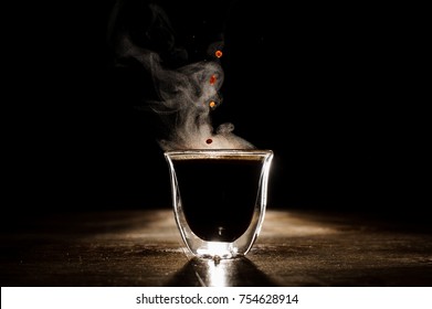 Hot Coffee Drink With Steam Spilling From Clear Glass Coffee Cup On The Dark Background. Coffee Concept