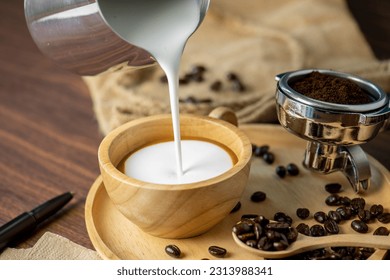 Hot coffee espresso latte with milk froth foam in wood cup. barista pouring milk liquid froth foam to wood cup of espresso for make creamy cappuccino hot drink. - Powered by Shutterstock