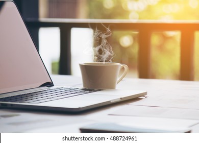 Hot Coffee And Laptop Seeing The Screen On The Cozy Desk On Relaxing Work Morning Sunrise Or Evening Sunset At The Office. Selective Focus.