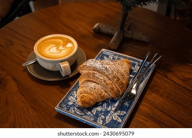 Hot coffee latte with latte art milk foam in cup mug with Croissant on wood desk on top view. As breakfast In a coffee shop at the cafe,during business work concept,vintage style