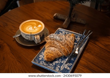 Hot coffee latte with latte art milk foam in cup mug with Croissant on wood desk on top view. As breakfast In a coffee shop at the cafe,during business work concept,vintage style