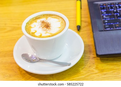 hot coffee on the table and laptop on background