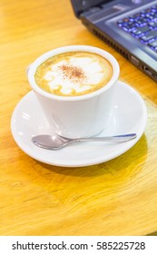 hot coffee on the table and laptop on background