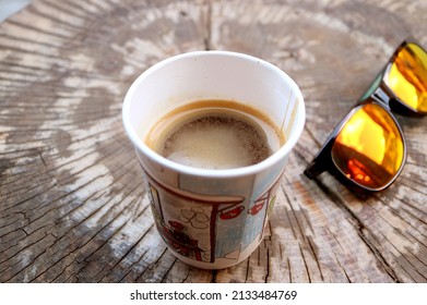 Hot Coffee In A Paper Cup On Tree Stump Table With Sunglasses