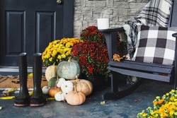 Hot Coffee Sitting On Rocking Chair On Front Porch That Has Been Decorated For Autumn With White, Orange, Grey Pumpkins, Rain Boots And Mums. Selective Focus With Blurred Foreground And Background.