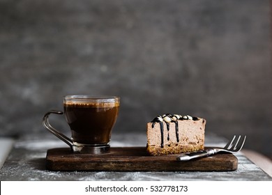 Hot Coffee And  Slice Of Raw Chocolate Mousse Cake With Cashew, Hazelnuts And Dark Chocolate Glaze Topping On A Wooden And Grey Background. Vegan Sugar Gluten Free Dessert. Copy Space, Horizontal