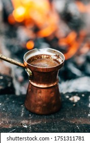 Hot coffee in turkish copper cup (cezve) isolated on bonfire and coal background