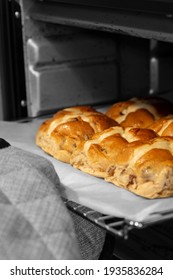 Hot Cross Buns Cooked In An Electric Oven.  Taken Out By A Person Wearing Oven Gloves