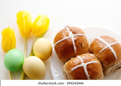 Hot cross buns with yellow and green eggs and yellow tulips. Easter. Good Friday