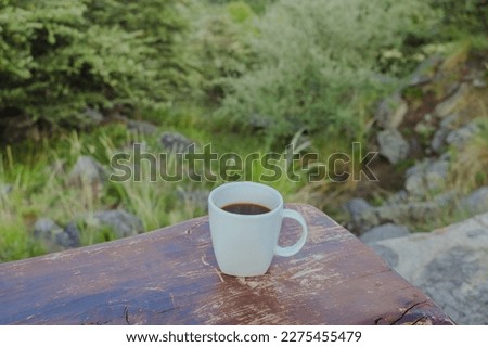 Hot Cup of Coffee in a Cold Morning. Coffee on a Wooden Table with forest-nature Background