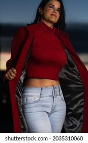 Hot Curvy Woman In Red Turtleneck Crop Top And In A Red Jacket With Blue Jeans. Outdoor Blue Hour Skyscape Background. 