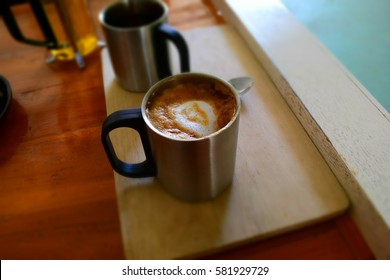 Hot dark coffee in stainless cup with cup of hot tea and stainless spoon on the wood. Dark coffee concept.