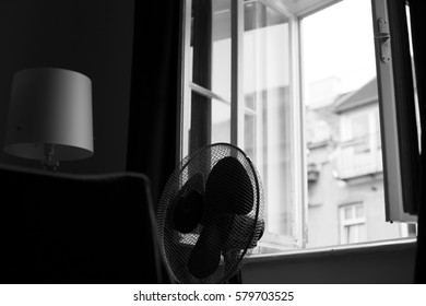 Hot Day In Vienna. Indoor Black And White Capture Of A Fan In Front Of Window.
