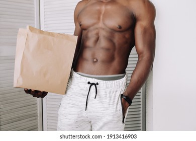 Hot Delivery. Every Woman's Dream. Pumped Up Handsome Black Man Holding A Craft Bag On A White Background. Cubes On The Stomach. Space For The Logo.Sexy Delivery.