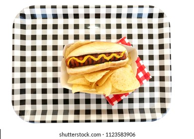 Hot Dog. Hot Dog In Bun And Potato Chips With Mustard Squiggle On A Black And White Checker Serving Tray. Isolated On White. Room For Text. 