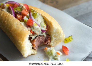 Hot Dog With Coleslaw, Tomato, Onions, Relish And Bite Missing. 