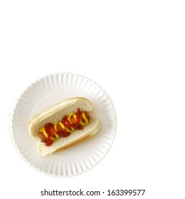 Hot Dog On A Bun On A White Paper Plate With Ketchup And Mustard