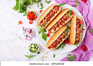 Hot Dog With Sausage. Bacon, Cucumber, Tomato And Red Onion On White Plate. Top View. Flat Lay.