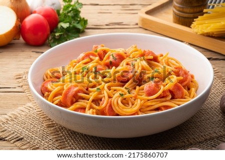 Hot dog or sausage stuffed with spaghetti in tomato pork sauce in white plate
