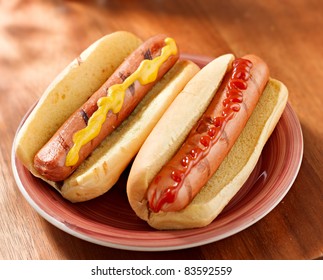 hot dog- two on a plate with ketchup and mustard all alone
