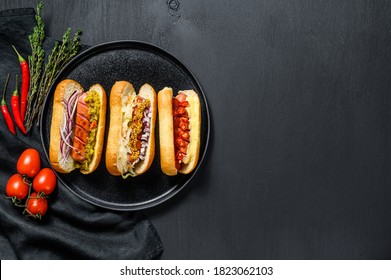 Hot dogs with assorted toppings. Delicious hot-dogs with pork and beef sausages. Black background. Top view. Copy space