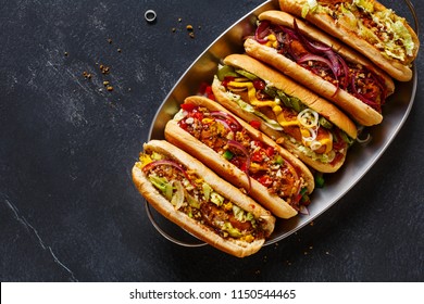 Hot dogs fully loaded with assorted toppings on a tray. Top view