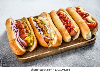 Hot dogs fully loaded with assorted toppings on a tray. Delicious hot-dogs with pork and beef sausages. White background. Top view.