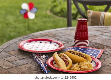 Hot Dogs At A July 4th Cookout Are Dressed With Ketchup And Mustard And Are Served With Potato Chips.  This Image Is In One In A Series Of Patriotically Themed Images.