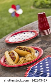 Hot Dogs At A July 4th Cookout Are Dressed With Ketchup And Mustard And Are Served With Potato Chips.  Selective Focus Was Used On This Image Which Is In A Series Of Patriotically Themed Images.