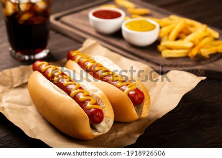 Hot dogs with ketchup, yellow mustard, french fries and soda. Image with selective focus.