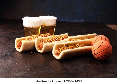 Hot Dogs With Mustard And Ketchup On The Table With Draft Beer. Television, TV Watching Basketball Game With Eating Snacks And Drinking Beer 