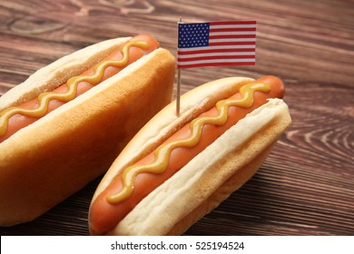 Hot dogs with mustard and small USA flag on wooden background - Powered by Shutterstock