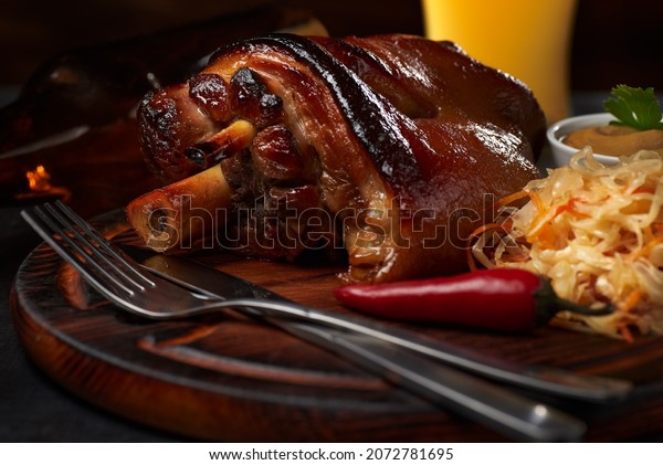 Hot\
eisbeine (pork knee)  with braised sauerkraut cabbage and craft\
beer on a dark and wooden background. Autumn food concept with copy\
space. Macro photo with shallow depth of\
field.