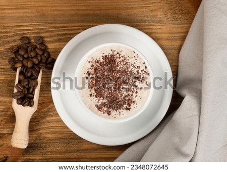 Hot espresso cup with chocolate and coffee beans on brown wooden table background top view. White coffeecup or mug with black beverage topview