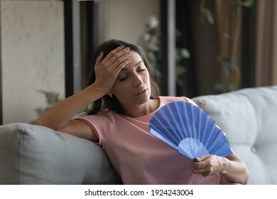 Too Hot. Exhausted Indian Female Suffer From Heat In Modern Apartment Use Hand Fan Feel Lack Of Air Conditioning. Unhappy Young Mixed Race Female Complaining On High Temperature At Home Hard To Breath