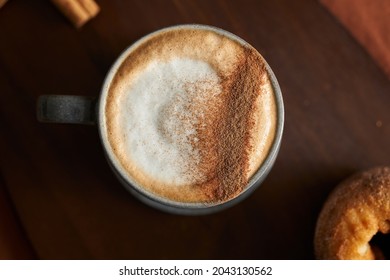 A hot and fresh cinnamon coffee on a cup and cinnamon stick, accompanying with a cinnamon donuts cover with cinnamon icing. - Powered by Shutterstock