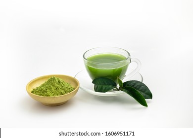 Hot Fresh Green Tea Drink In Through White Glass Cup And Dishware. Place With Deep Green Tea Leaves And Extract Powder In Wooden Bowl On White Background.