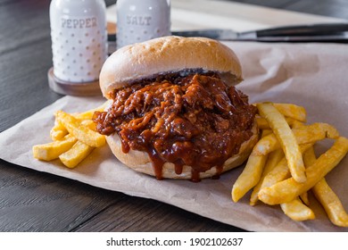 Hot, fresh pulled pork barbecue sandwich with french fried potatoes on brown paper