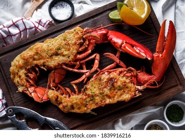 Hot and freshly baked halved Lobster with butter. Fresh, juicy, tasty and flavorful bright red Maine Lobster or American lobster on a hand of waitperson, ready to be served.