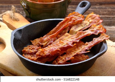 Hot Fried Bacon Pieces In A Cast Iron Skillet
