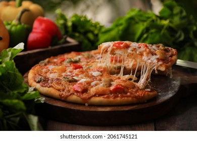 Hot Fuming Pizza On A Wooden Table With Cheese Stretch ,cheese String With All The Ingredients Closeup With Selective Focus And Blur