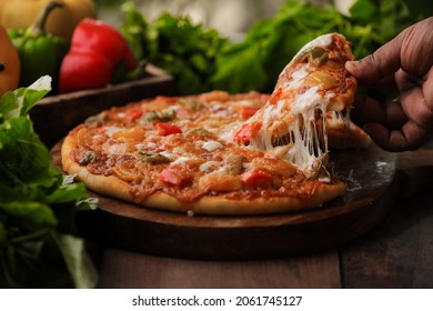 Hot Fuming Pizza On A Wooden Table With Cheese Stretch ,cheese String With All The Ingredients Closeup With Selective Focus And Blur