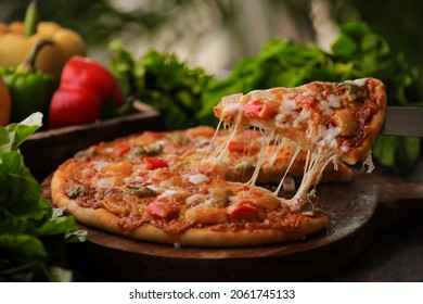 Hot Fuming Pizza On A Wooden Table With Cheese Stretch ,cheese String With All The Ingredients Closeup With Selective Focus And Blur