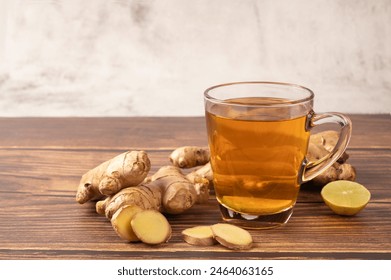 Hot ginger tea with ginger and lime on wooden table.