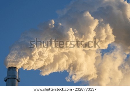 Hot Glowing colorful Smoke Plume sunlit while emitting Greenhouse gas into atmosphere during late evening from Paper mill Industry at Pitea Sweden.